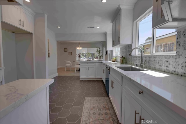 kitchen featuring sink, light stone countertops, pendant lighting, stainless steel dishwasher, and white cabinetry