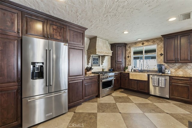 kitchen featuring custom exhaust hood, high end appliances, decorative backsplash, sink, and light stone counters