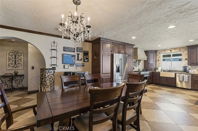 dining space featuring a textured ceiling, an inviting chandelier, ornamental molding, and sink