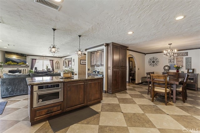 kitchen featuring decorative light fixtures, oven, a center island, crown molding, and dark brown cabinetry