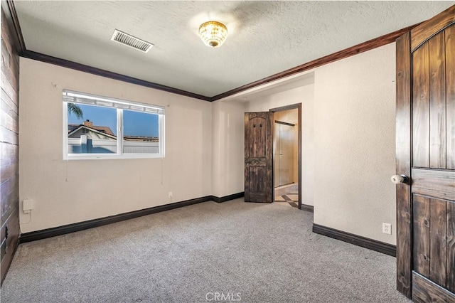 spare room featuring light colored carpet, a textured ceiling, and crown molding