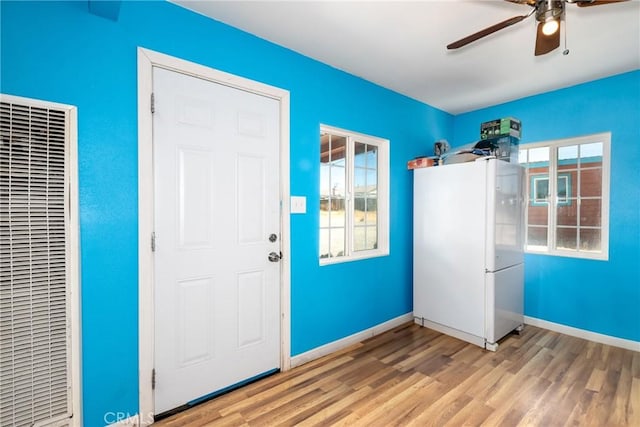 foyer entrance featuring baseboards, a ceiling fan, wood finished floors, and a heating unit