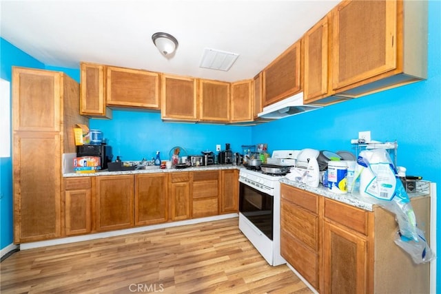 kitchen featuring white gas range, visible vents, light wood-type flooring, light countertops, and under cabinet range hood