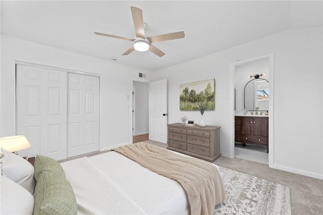 bedroom featuring connected bathroom, ceiling fan, a closet, and light carpet