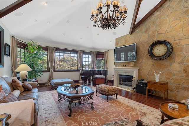 living room featuring wood finished floors, high vaulted ceiling, a glass covered fireplace, beamed ceiling, and a chandelier