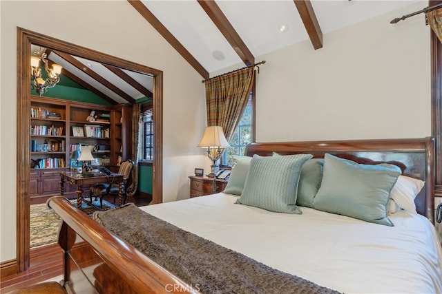 bedroom with lofted ceiling with beams, a barn door, and wood finished floors