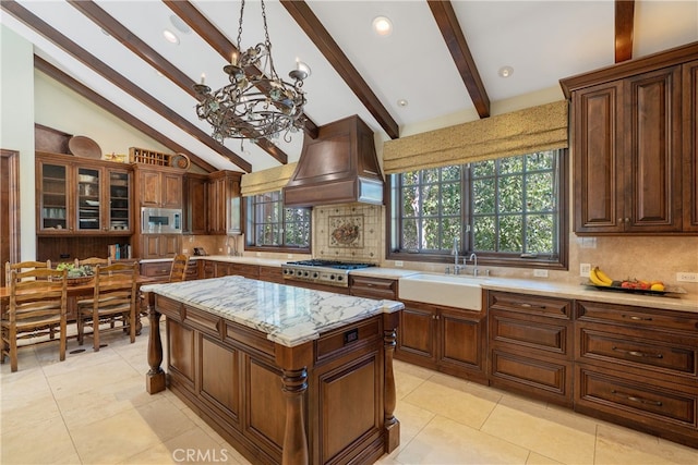 kitchen with a sink, lofted ceiling with beams, stainless steel appliances, custom exhaust hood, and a chandelier