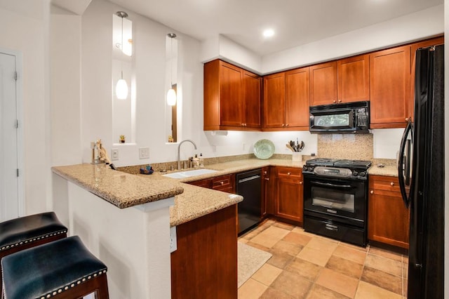 kitchen with a kitchen bar, black appliances, decorative light fixtures, light stone counters, and kitchen peninsula