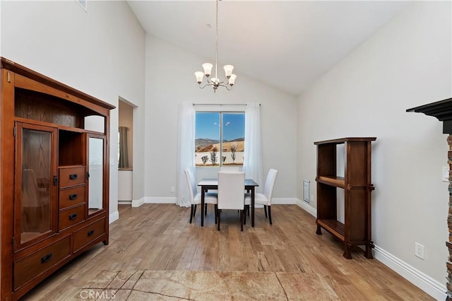 dining area with light hardwood / wood-style floors, high vaulted ceiling, and a chandelier