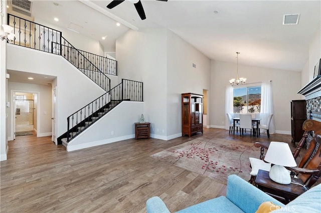 living room featuring high vaulted ceiling, ceiling fan with notable chandelier, and hardwood / wood-style flooring