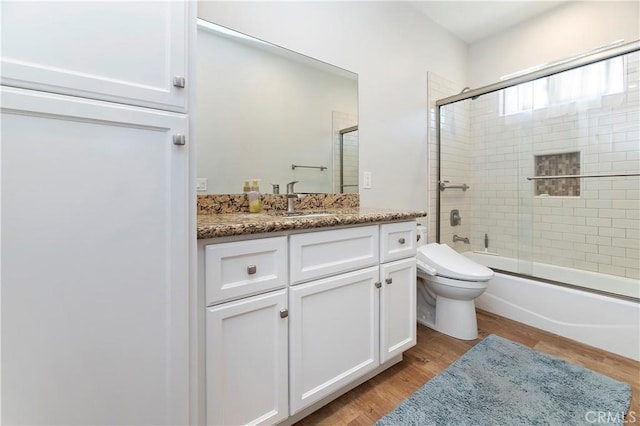 full bathroom with shower / bath combination with glass door, toilet, vanity, and hardwood / wood-style flooring