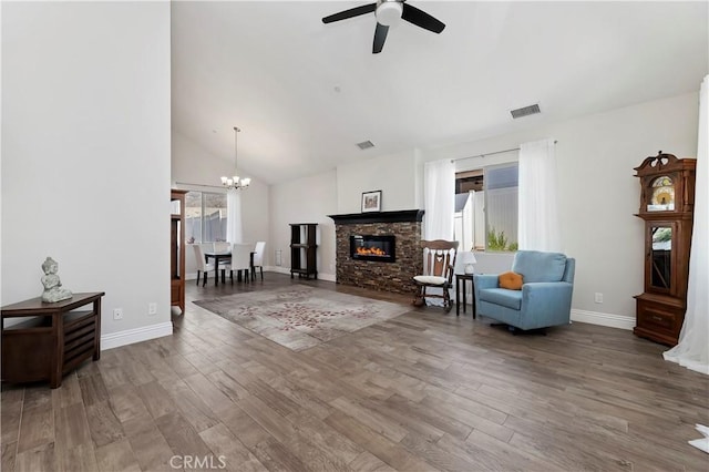 living room with a fireplace, wood-type flooring, ceiling fan with notable chandelier, and vaulted ceiling