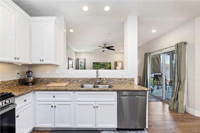 kitchen with appliances with stainless steel finishes, sink, dark stone countertops, light hardwood / wood-style floors, and white cabinetry