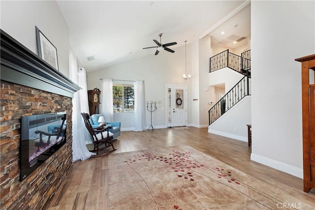 unfurnished living room with hardwood / wood-style flooring, ceiling fan, a stone fireplace, and high vaulted ceiling