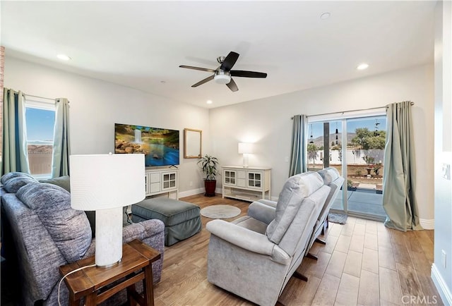 living room with ceiling fan and light hardwood / wood-style flooring