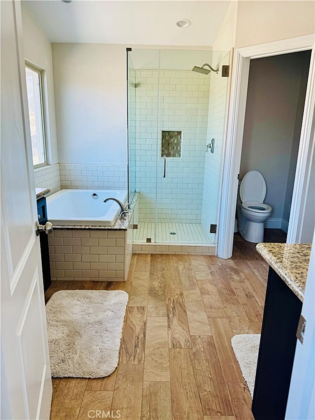 full bathroom featuring plus walk in shower, hardwood / wood-style floors, vanity, and toilet