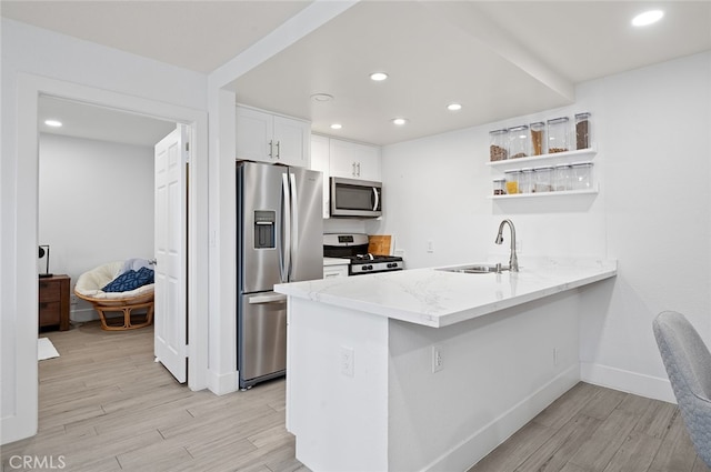 kitchen with light hardwood / wood-style floors, sink, white cabinetry, kitchen peninsula, and stainless steel appliances