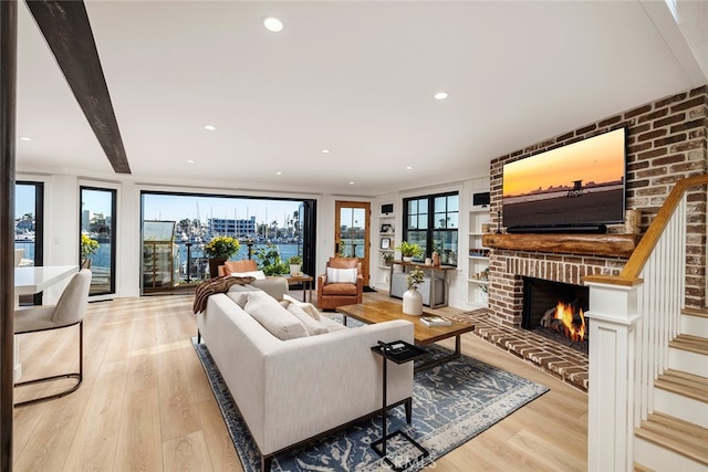 living room with a brick fireplace, built in features, light wood finished floors, and recessed lighting