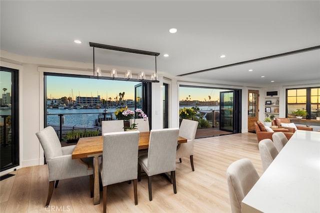 dining room with light hardwood / wood-style floors and a water view