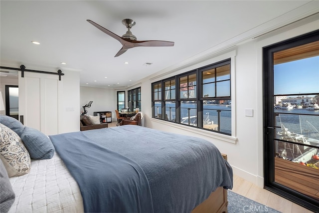 bedroom with a water view, multiple windows, ceiling fan, and a barn door