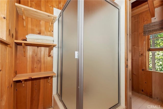 bathroom with wood walls, a shower with shower door, and hardwood / wood-style flooring