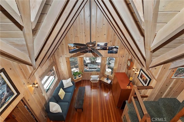 living room with wood walls, dark wood-type flooring, high vaulted ceiling, ceiling fan, and wood ceiling