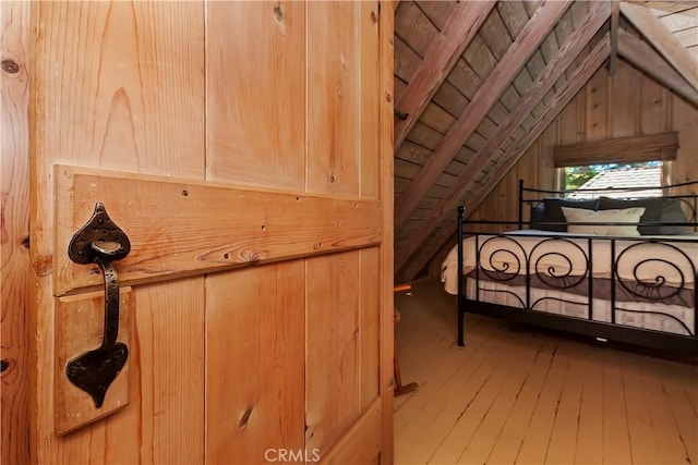 bedroom with wood walls, lofted ceiling, and hardwood / wood-style flooring