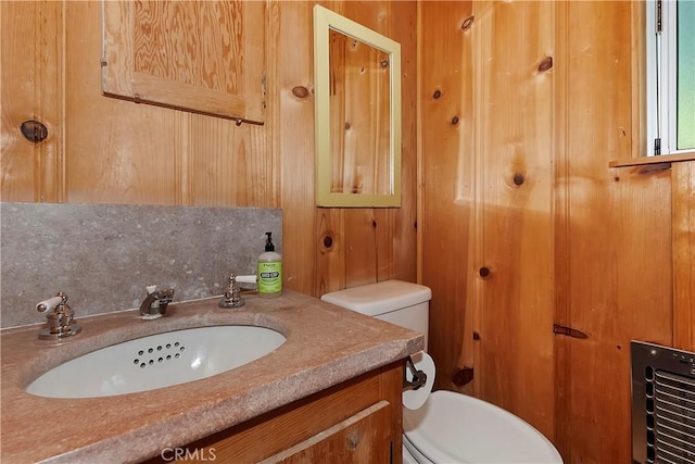 bathroom featuring vanity, toilet, backsplash, and wooden walls