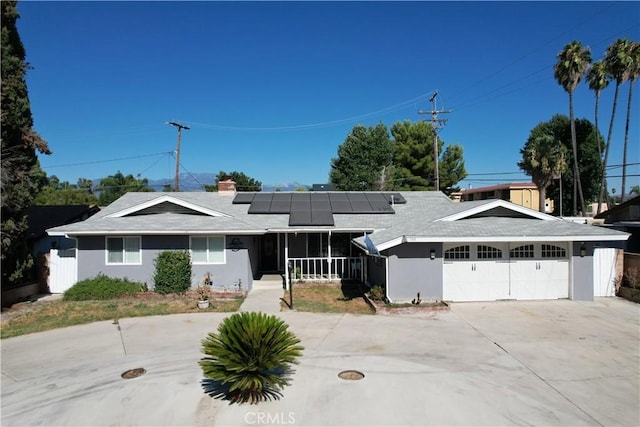 single story home with covered porch, a garage, and solar panels