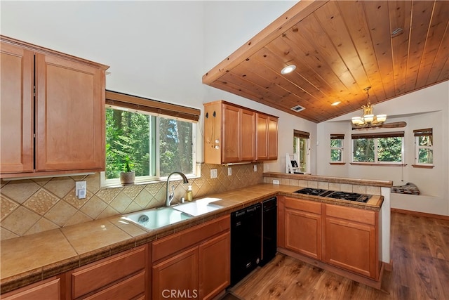 kitchen featuring dishwasher, tile counters, hardwood / wood-style floors, sink, and a notable chandelier