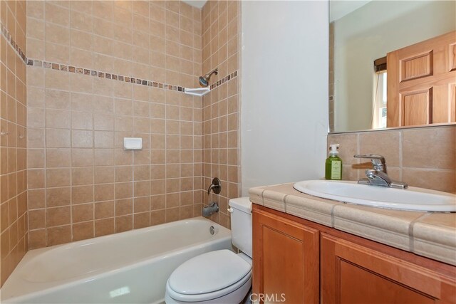 full bathroom featuring tiled shower / bath, vanity, toilet, and decorative backsplash