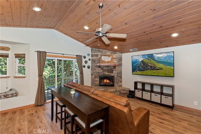 interior space with ceiling fan, light hardwood / wood-style floors, a stone fireplace, wooden ceiling, and vaulted ceiling