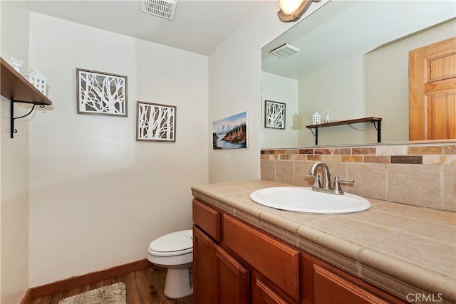 bathroom with wood-type flooring, tasteful backsplash, vanity, and toilet