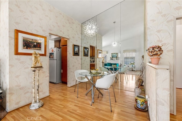 dining area with a towering ceiling, wood-type flooring, and a notable chandelier