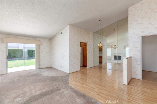 unfurnished living room with hardwood / wood-style flooring, vaulted ceiling, and a textured ceiling