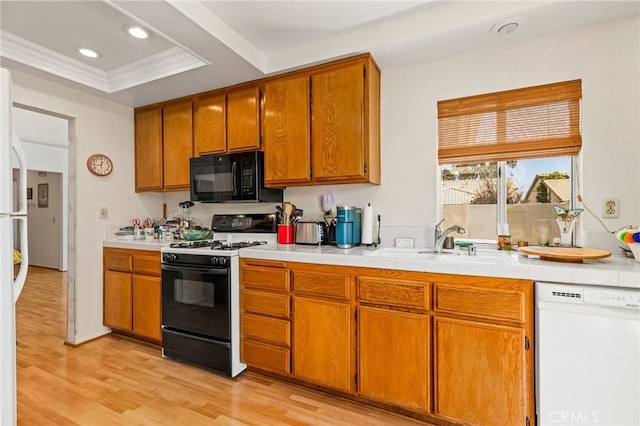 kitchen with ornamental molding, white dishwasher, a raised ceiling, gas stove, and light wood-type flooring