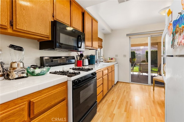 kitchen featuring light hardwood / wood-style flooring, sink, white appliances, and tile countertops