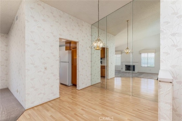 unfurnished living room with high vaulted ceiling, a fireplace, hardwood / wood-style floors, and a textured ceiling