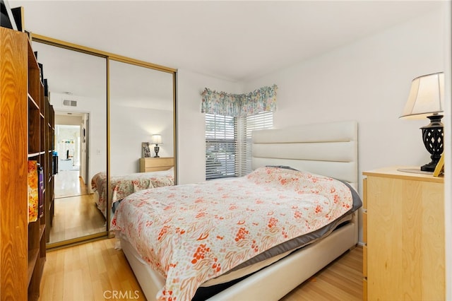 bedroom with light hardwood / wood-style floors and a closet