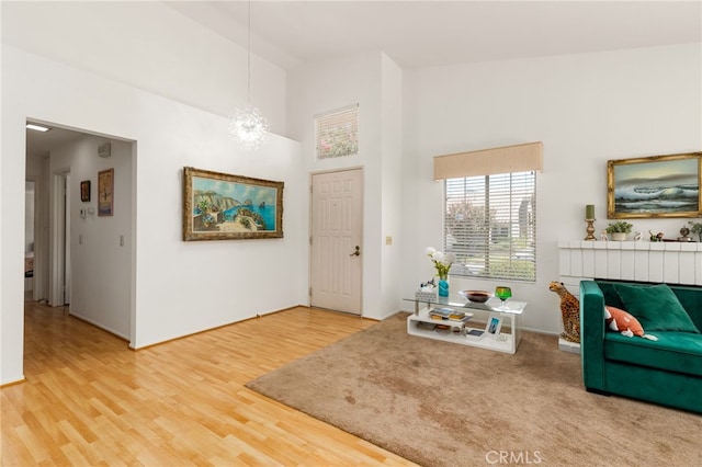 living area with hardwood / wood-style flooring, high vaulted ceiling, and a notable chandelier