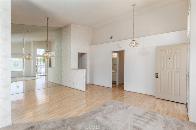 unfurnished room featuring hardwood / wood-style flooring, a notable chandelier, and high vaulted ceiling