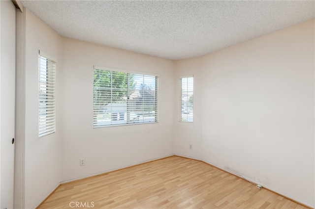 spare room featuring a textured ceiling and light wood-type flooring