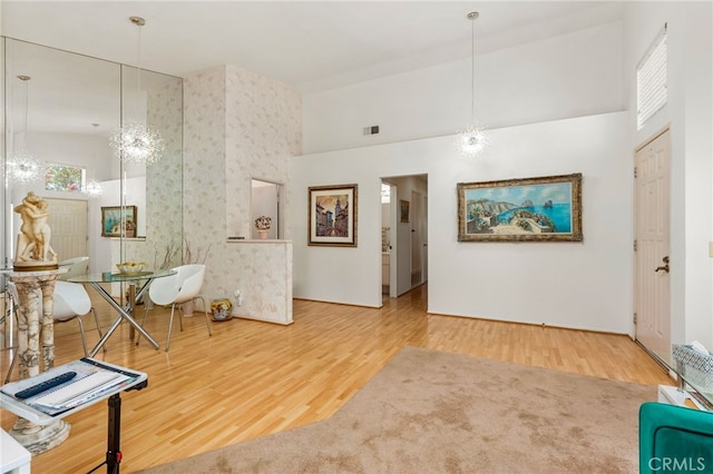 living area featuring a high ceiling, wood-type flooring, and an inviting chandelier