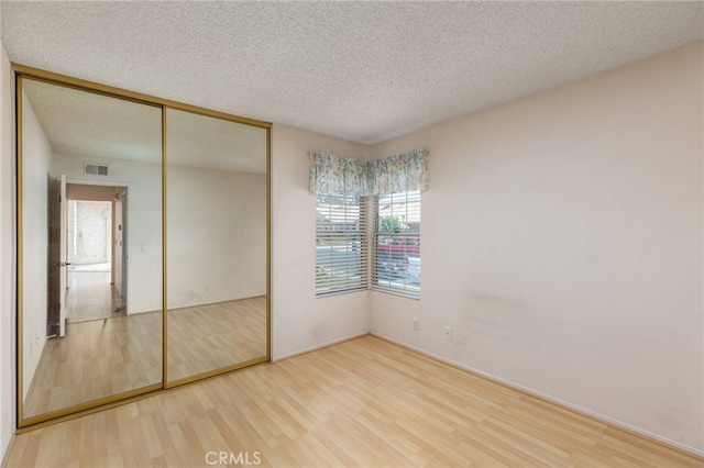 unfurnished bedroom with a closet, hardwood / wood-style floors, and a textured ceiling