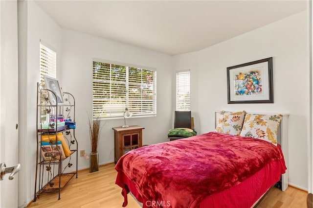 bedroom with multiple windows and light hardwood / wood-style flooring