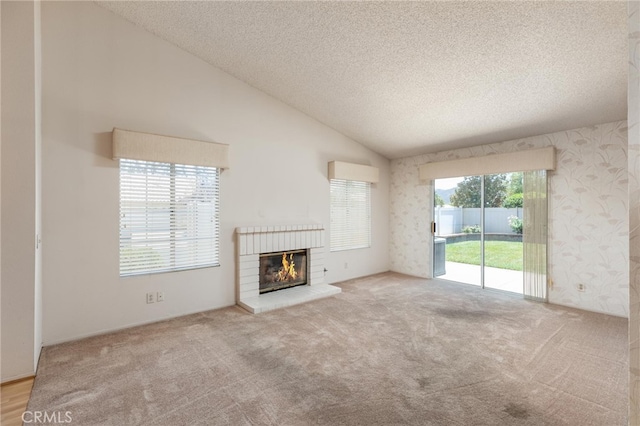 unfurnished living room with high vaulted ceiling, carpet floors, a brick fireplace, and a textured ceiling