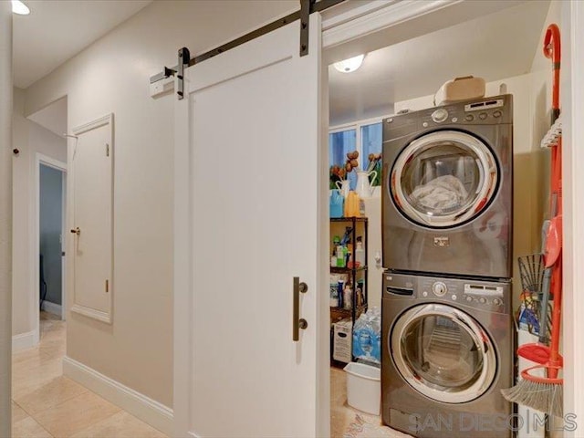 clothes washing area featuring stacked washer / dryer and a barn door