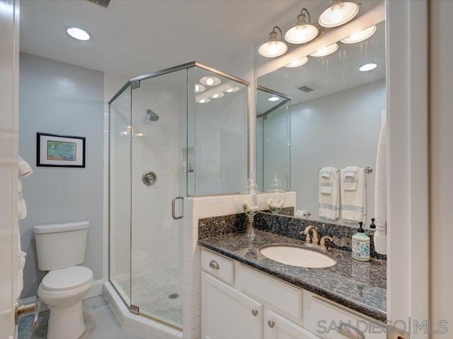 bathroom featuring toilet, tile patterned floors, a shower with shower door, and vanity