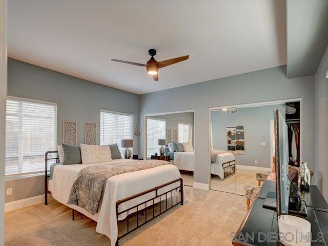 bedroom with ceiling fan, light colored carpet, and multiple windows