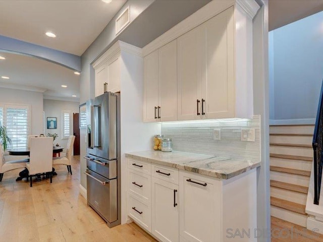 kitchen with decorative backsplash, light stone countertops, white cabinetry, and high end fridge